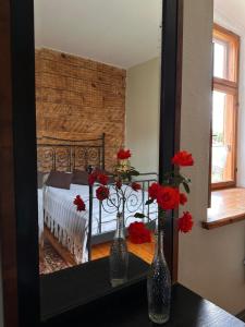 two vases with red flowers on a table in front of a mirror at Baznīcas ielas apartamenti in Kuldīga