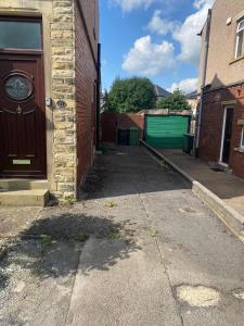 an alley with a brown door and a green garage at Huddersfield 2 bedroom house in Huddersfield
