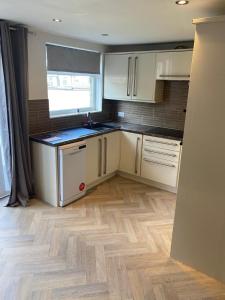 a kitchen with white cabinets and a wooden floor at Huddersfield 2 bedroom house in Huddersfield