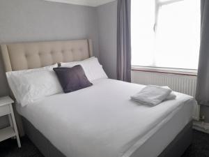 uma grande cama branca com duas almofadas e uma janela em Bright 4-Bed house 15 min to Manchester Centre em Manchester