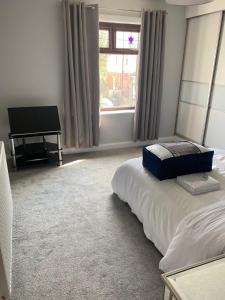 - une chambre avec un lit et un piano à côté d'une fenêtre dans l'établissement Huddersfield 2 bedroom house, à Huddersfield