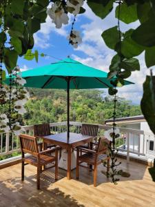 une table avec deux chaises et un parasol vert sur une terrasse dans l'établissement The Chocolate Factory House, Kandy, à Kandy
