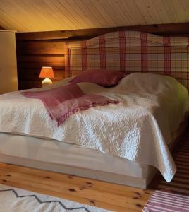 a bed with a white comforter and a lamp at "SoFly Lodge", Charm and Elegance in Noresund