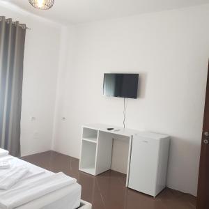 a room with a white desk with a tv on the wall at Pomegranates & Olives Guesthouse in Durrës