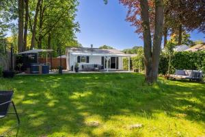 une cour avec une maison blanche et un arbre dans l'établissement Bed & outdoor wellness - natuurhuisje Oisterwijk, à Oisterwijk