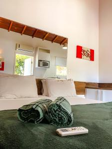 a bed with a remote control sitting on top of it at Pousada Jungle Beach Maresias in Maresias