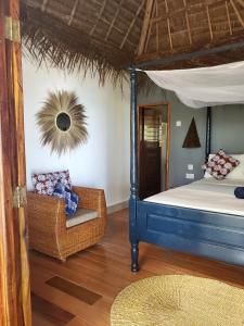 a bedroom with a blue bed and a chair at Promised Land Lodge in Kizimkazi