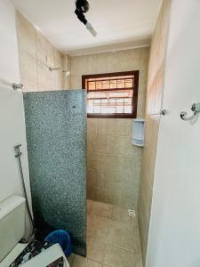 a shower with a glass door in a bathroom at A 200m da praia de Taperapuã Axé Moi 2 suítes, churrasqueira privativa, piscina, sauna portaria 24hrs e internet privativa 300MBPS in Porto Seguro