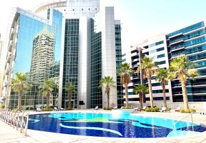 a large swimming pool with palm trees and buildings at The Waves 241 Dubai Marina in Dubai
