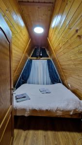 Cama pequeña en habitación de madera con techo en Cabana Alpin, en Vatra Dornei