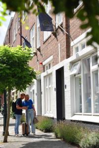 deux personnes debout sur un trottoir près d'un bâtiment dans l'établissement Hotel Bries Den Haag - Scheveningen, à La Haye