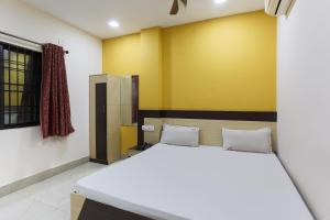 - une chambre avec un lit et un mur jaune dans l'établissement SPOT ON 81399 Hotel Rainbow Regency, à Rourkela
