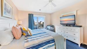 a bedroom with a bed with a television and a dresser at Lighthouse Point Villas in Ocean City