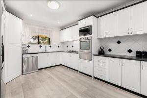 una grande cucina bianca con armadi e elettrodomestici bianchi di 5 bedroom home in a quiet area a Mill Park