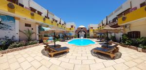 Delta Dahab Hotel في دهب: ساحة مع مسبح وكراسي ومظلات