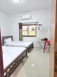 a room with two beds and a table and a window at Inner Homestay Betong-อินเนอร์ โฮมสเตย์ เบตง in Betong