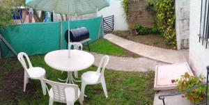 une table et des chaises avec un parasol et un grill dans l'établissement Posada "Doña Lucia" Para 3 Personas COCHERA PRIVADA GRATIS, à Mar del Plata