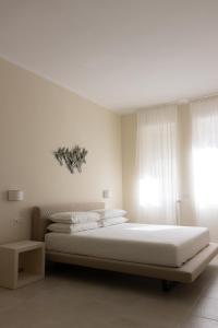 a white bedroom with a large bed and a window at Oronti Accommodations in Lecce