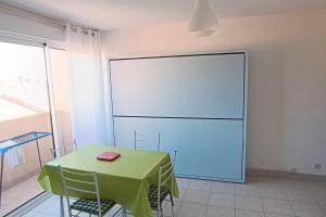 a green table and chairs in a room with a large screen at Studio maison de la mer in Saint Pierre La Mer +1 photo