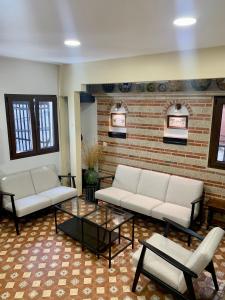 Casa Rural Chorrito 1 في لا ألبيركا: غرفة معيشة بها كنبتين بيضاء وجدار من الطوب