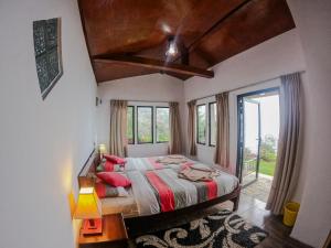 a bedroom with a large bed with a large window at Hill Safari - Tea Estate Villa in Ohiya