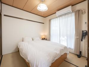 une chambre avec un lit blanc et une fenêtre dans l'établissement Vacation Inn Haneda 1, à Tokyo