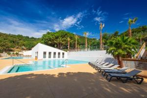 a swimming pool with lounge chairs next to a resort at Domaine de Miremer in La Garde-Freinet