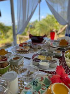 einen Tisch mit Speisen, Schalen und Teller mit Lebensmitteln in der Unterkunft Eco-Pousada Casa Bobô in Ilha de Boipeba