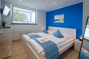 a blue bedroom with a white bed with blue pillows at CBlue: Küstenzauber barrierefrei mit Balkon in Heiligenhafen