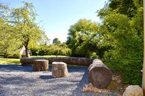 un banco de troncos en un parque con árboles en Gîte du Rochelu 4 Étoiles 5000 m2 of Garden, near to Mont Saint Michel & Granville island, en Bourguenolles