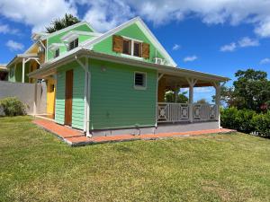 una casa verde y amarilla con patio en La Belle Epoque (3*) - Maison avec vue sur mer à Bouillante en Bouillante