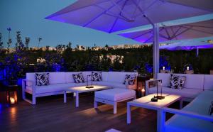 a patio with white couches and tables and an umbrella at LHP Napoli Palace & SPA in Naples