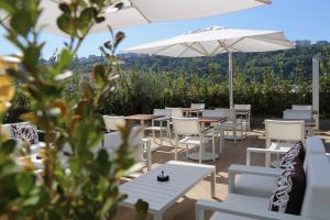 a patio with tables and chairs and an umbrella at LHP Napoli Palace & SPA in Naples
