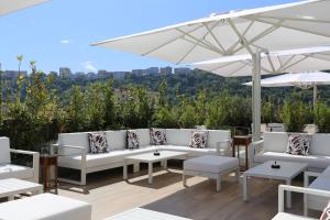 een patio met witte banken en tafels en een parasol bij LHP Napoli Palace & SPA in Napels
