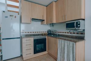 a kitchen with wooden cabinets and a sink and a refrigerator at Vivienda Turística Sunbeach-Xilxes VT-42192-CS in Xilxes