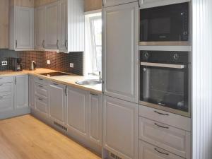 una cucina con armadi bianchi, lavandino e forno a microonde di Holiday home averøy VI ad Averoy