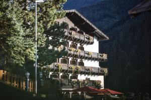 a building with a balcony with flowers on it at Berghotel Basur - Das Schihotel am Arlberg in Flirsch