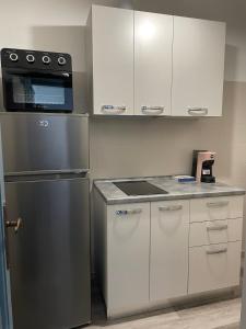 a kitchen with a stainless steel refrigerator and white cabinets at appartamento dell'anfiteatro in Spoleto
