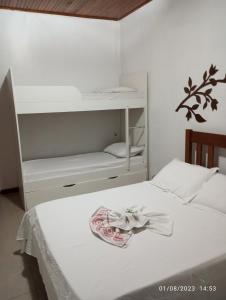 a bedroom with a white bed and a shelf at Pousada Longe Vista in Tibagi