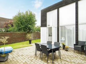 a patio with a table and chairs in a backyard at Holiday home Gilleleje CVII in Gilleleje