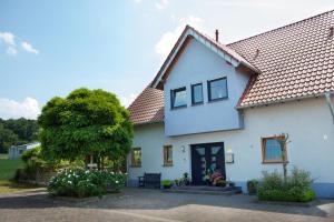 a white house with a tree in front of it at Ferienwohnung Am Korretsberg in Kruft