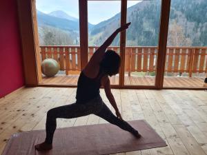 a woman doing a yoga pose in front of a window at Le Chalet Du Blanc Spa yoga in Aillon-le-Jeune