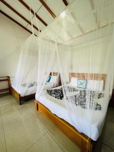 2 łóżka w pokoju z moskitierą w obiekcie Racy Nature Cottage w mieście Ella