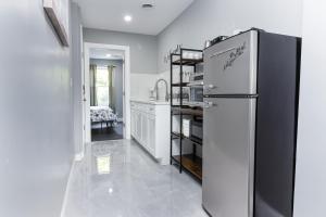 a white kitchen with a refrigerator in a room at Cozy Micro apartment Sleeps 4 Minutes from Niagara Falls in Niagara Falls