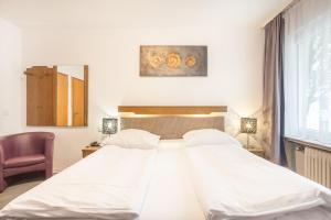 a bedroom with a large white bed and a chair at Hotel Union in Dortmund