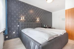 a bedroom with a large bed with a gray wall at Hotel Union by TM in Dortmund
