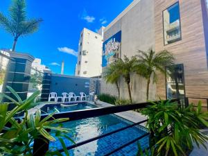 a swimming pool in front of a building with palm trees at Marmeu Tombo com Hidro Aquecida Privativa in Guarujá