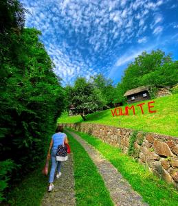 a woman walking down a path next to a stone wall at Brvnare Platan - prirodna oaza in Vrdnik