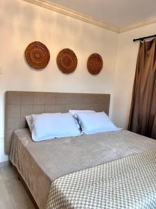 1 cama con 2 almohadas y 3 platos en la pared en casa de praia, en Bombinhas