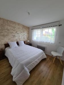 um quarto com uma grande cama branca e uma janela em Le gite de la fontaine em Poyanne
